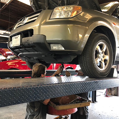 Circle D Transmission Technician Servicing a Honda SUV on Racks